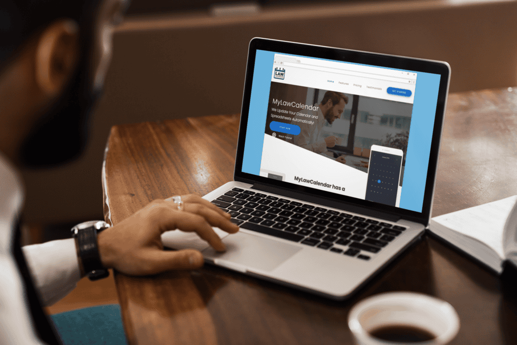 A person is using a laptop displaying the MyLawCalendar website. The setting is a wooden table, suggesting a workspace atmosphere. The tone is productive.