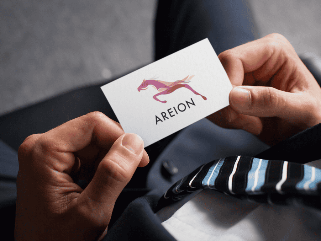 A person in a suit holds a business card with a stylized horse logo and "AREION" text. The scene conveys professionalism and elegance.
