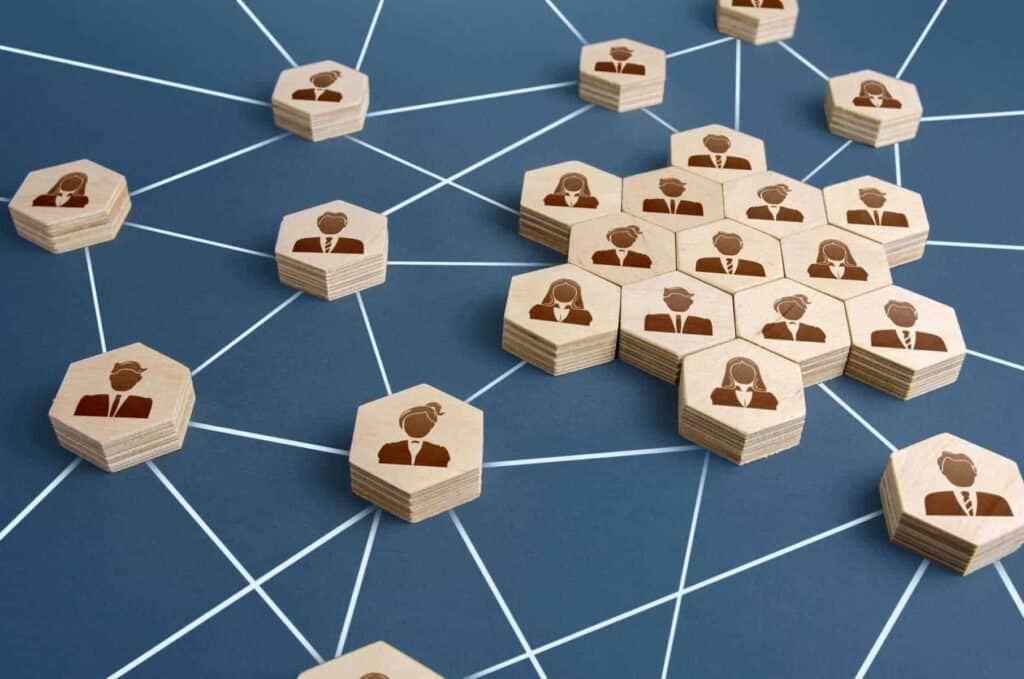 Wooden hexagons with people icons are connected by white lines on a blue background, illustrating a network or social connections concept.